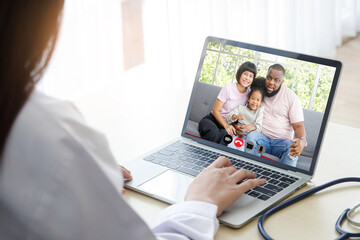 A woman doctor chatting over an online video call with an African-American family of patients. Concept of communicating through technology online. Doctors can examine patients through video calls.