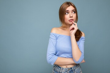 Photo portrait of thoughtful young nice beautiful blonde woman with sincere emotions wearing trendy blue crop top isolated over background with empty space and thinking