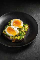 Poached egg on avocado toast on a black plate