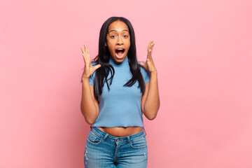 young black woman feeling happy, excited, surprised or shocked, smiling and astonished at something...