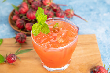 Iced roselle tea glass with fresh roselle fruit on wooden table for healthy herbal drink concept. herbal organic tea for good healthy.