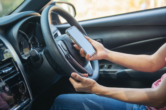 Mockup image of a woman holding and using mobile phone with blank screen while driver a car, for GPS, Lifestyles photo in car, Interior, front view. With woman hand holding phone.