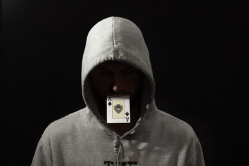Man in hoodie with playing cards in his mouth