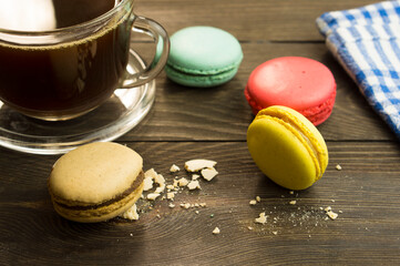 Cup of coffee on a wooden table with macarons, beautiful breakfast concept. Sun ray on a cup of coffee in the morning.