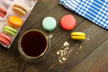 Cup of coffee on a wooden table with macarons, beautiful breakfast concept. Sun ray on a cup of coffee in the morning.