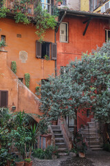 Fototapeta premium kolorowe stare kamienice z wejściem po schodach wśród zielonych drzew z drewnianymi oknami i żaluzjami