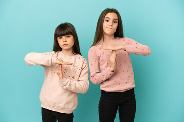 Little sisters girls isolated on blue background making stop gesture with her hand to stop an act