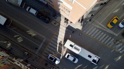 Aerial view of crosswalk and intersection road at the city center. The sunlight is coming through the buildings. people cross the pedestrian path also.