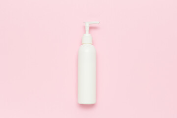 White cream dispenser on soft pink background