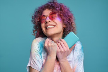 Happy young woman with Holi colors and smartphone