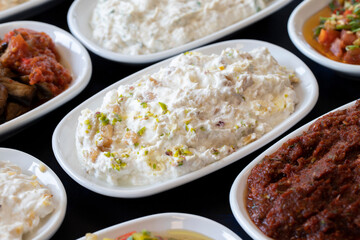 Traditional Turkish and Greek food appetizer table. Grilled eggplant salad (saksuka), Anamur salad, Baba Ghanoush (Mutabbal), pasha appetizer, spicy paste or harissa, purslane salad. Selective focus