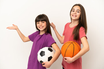 Little sisters playing football and basketball isolated on white background extending hands to the side for inviting to come