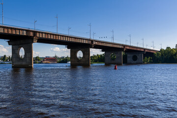 Fototapeta na wymiar Bridge on a river against a blue sky and clouds