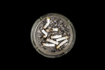 an ashtray with the cigarette butts in it. ash pot from the top point of view isolated on black background. the campaign issues on risk and addiction of smoking.