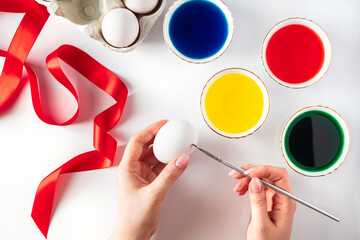 Young woman paints white eggs for easter.