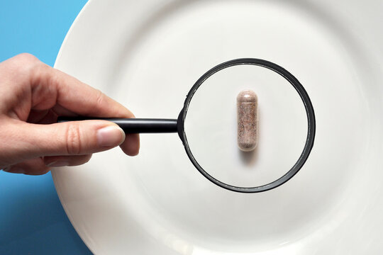 The person examines the pill. Study of the vitamin content in a tablet
