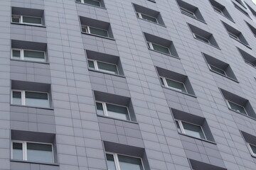 Plastic windows in a modern gray tiled brick high-rise house. Bottom view. Stock photo modern urban development for web and print.
