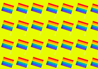 Pattern of rainbow flags, representative of the gay community, on a yellow background. Gay pride concept