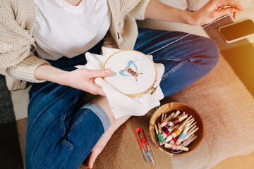 Young woman holding loop with embroidered picture of a bee. Top view.