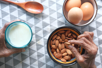  senior women holding a bowl on almond and a glass of milk 