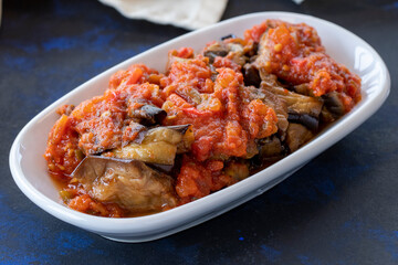 Grilled eggplant salad appetizer with tomato sauce (with eggplant sauce or saksuka). Traditional Middle Eastern meze beside the main course. Layout on dark wood