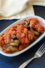 Grilled eggplant salad appetizer with tomato sauce (with eggplant sauce or saksuka). Traditional Middle Eastern meze beside the main course. Layout on dark wood