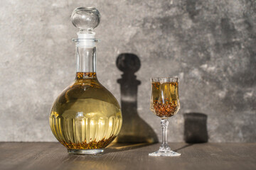 Homemade birch buds tincture in a glass bottle and a wine crystal glass on a wooden table background