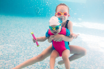 Underwater photo of young friends in swimming pool.