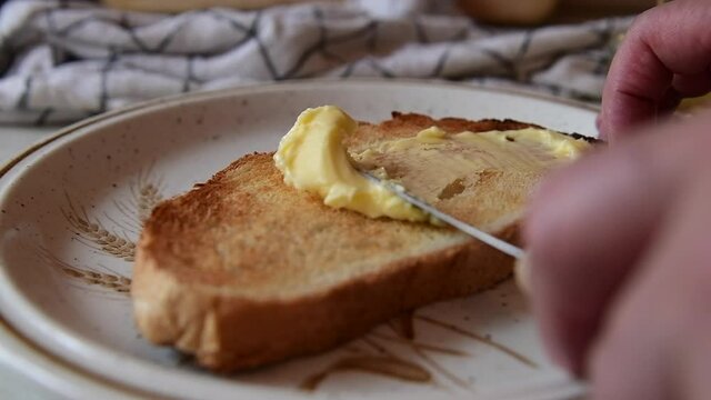 a slow motion of spreading butter on a piece of toast