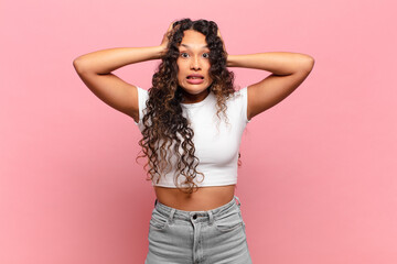 young hispanic woman feeling stressed, worried, anxious or scared, with hands on head, panicking at...