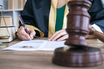 Woman lawyer working with contract papers and wooden gavel on tabel in courtroom. justice and law ,attorney, court judge, concept.