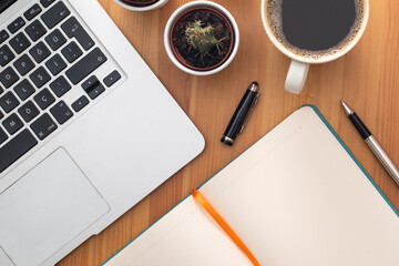 Wooden working desk with laptop computer, smartphone, office supplies and coffee