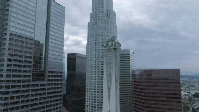 Rising aerial of the US Bank Tower surrounded by neighboring high rise buildings and a threatening overcast sky - Amazing Aerials of Building Clos - Los Angeles, California