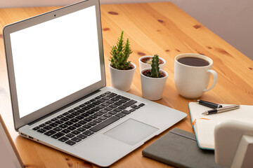 Wooden working desk with laptop computer, smartphone, office supplies and coffee