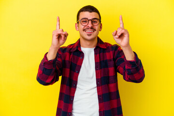 Young caucasian cool man isolated on yellow background indicates with both fore fingers up showing...