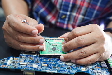 E-waste, technician repairing inside of hard disk by soldering iron. Integrated Circuit. the...