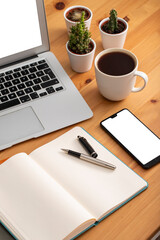 Wooden working desk with laptop computer, smartphone, office supplies and coffee