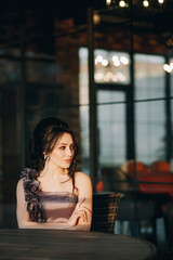 Vertical shot of nice looking girl sitting in street cafe and enjoying her time in the evening