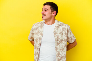 Young caucasian cool man isolated on yellow background confident keeping hands on hips.