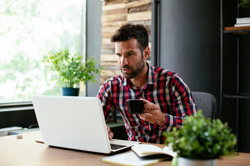 Young businessman drinking coffee in his office. Businessman on coffee break.