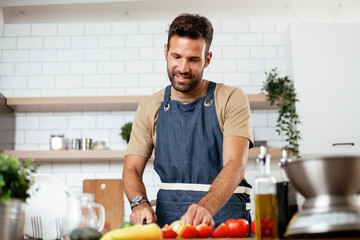 Handsome man preparing vegetable salad in the kitchen. Healthy Food. Vegan Salad..