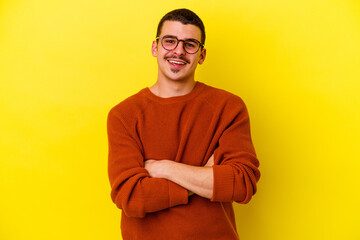 Young caucasian cool man isolated on yellow background who feels confident, crossing arms with determination.