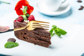 Delicious chocolate cake on plate with a cup of coffee on a blue background