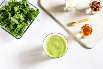 Healthy green kale smoothie with greek yogurt, almond n honey in glass isolated on white table background,top view. Kale is considered a superfood because it's a great source of vitamins and minerals.