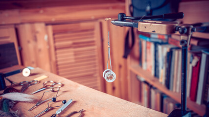 Fishing fly tying materials and tools on a wooden table - obrazy, fototapety, plakaty