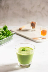 Obraz na płótnie Canvas Healthy green kale smoothie with greek yogurt, almond and honey in glass isolated on white table background. Kale is considered a superfood because it's a great source of vitamins and minerals.