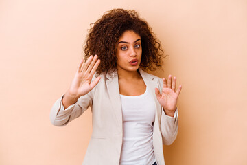 Young african american woman isolated on beige background rejecting someone showing a gesture of...
