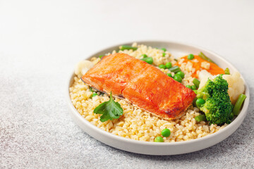 Salmon fillets with bulgur and vegetables in the plate. Diet nutrition.