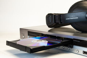 modern audio device with open tray, headphones  and laserdisc on white background close-up