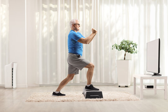 Mature Man Exercising On A Step Aerobic Platform In Front Of A Tv At Home